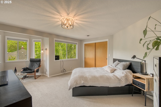 bedroom with carpet floors, baseboards, a chandelier, and a closet