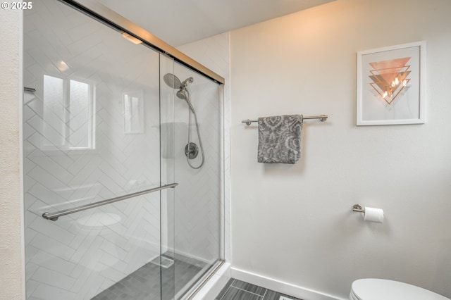 full bathroom with toilet, a shower stall, and baseboards