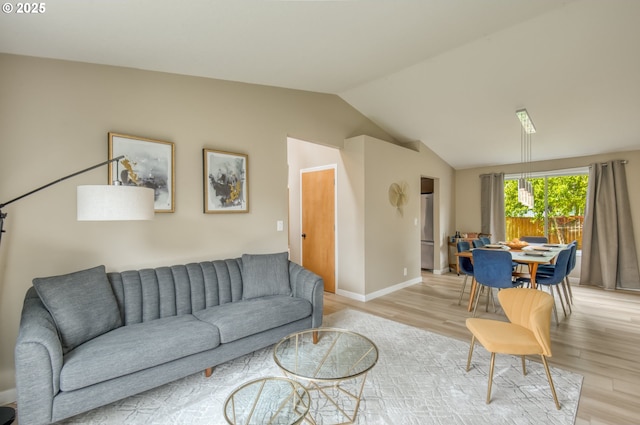living area with light wood finished floors, lofted ceiling, and baseboards