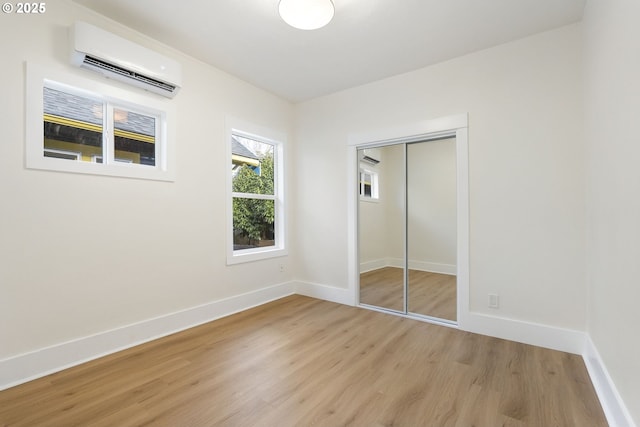 unfurnished bedroom featuring a closet, light hardwood / wood-style flooring, and an AC wall unit