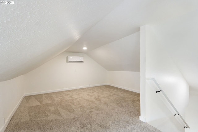 bonus room with a wall unit AC, light colored carpet, a textured ceiling, and vaulted ceiling