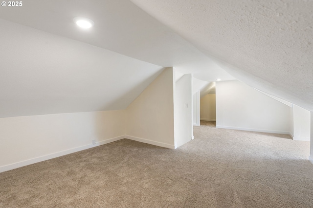 bonus room with lofted ceiling, a textured ceiling, and carpet