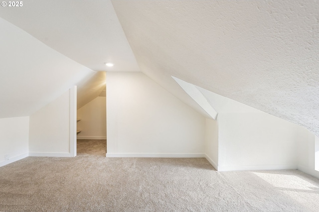 additional living space with lofted ceiling, light carpet, and a textured ceiling