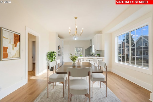 dining space with a notable chandelier and light hardwood / wood-style flooring