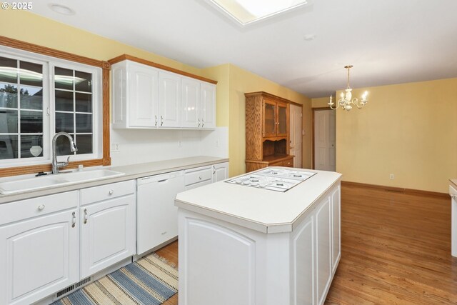 kitchen with white appliances, a sink, a center island, and light wood-type flooring