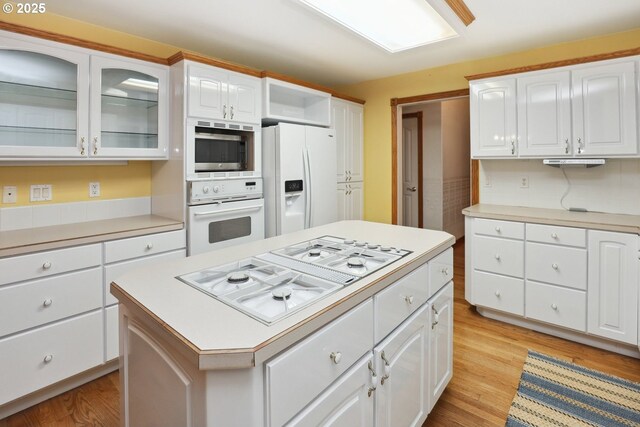 kitchen featuring white appliances, light wood-type flooring, light countertops, and white cabinetry