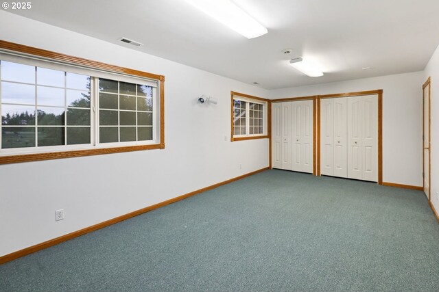 unfurnished bedroom with two closets, baseboards, and carpet floors