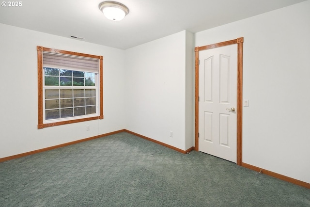 empty room with baseboards and dark carpet