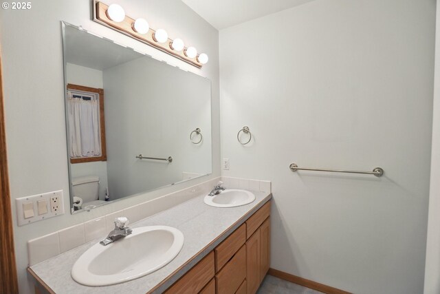 bathroom with double vanity and toilet
