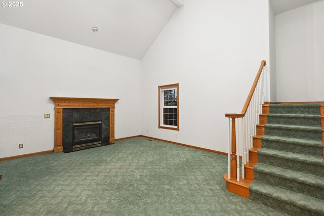 unfurnished living room with high vaulted ceiling, a tile fireplace, carpet, baseboards, and stairway