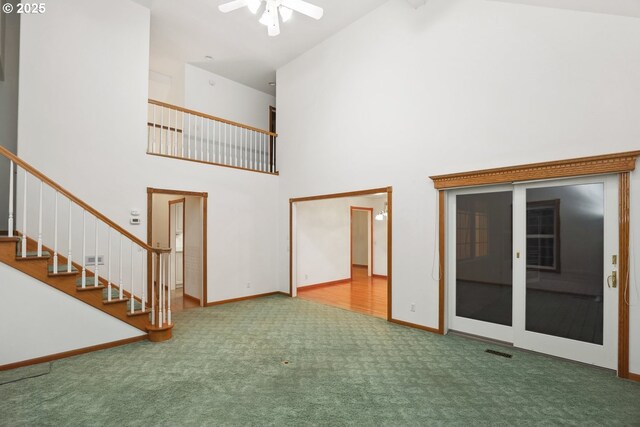 unfurnished living room featuring high vaulted ceiling, carpet floors, a ceiling fan, stairs, and baseboards