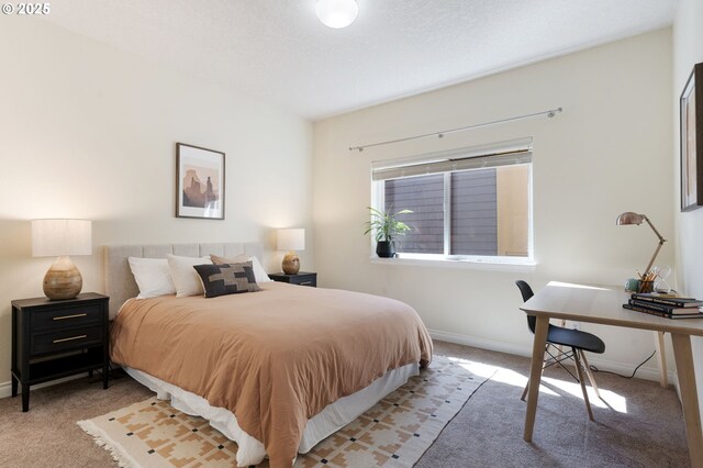 carpeted bedroom featuring baseboards and a desk