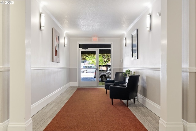 sitting room featuring a textured ceiling, ornamental molding, and carpet floors
