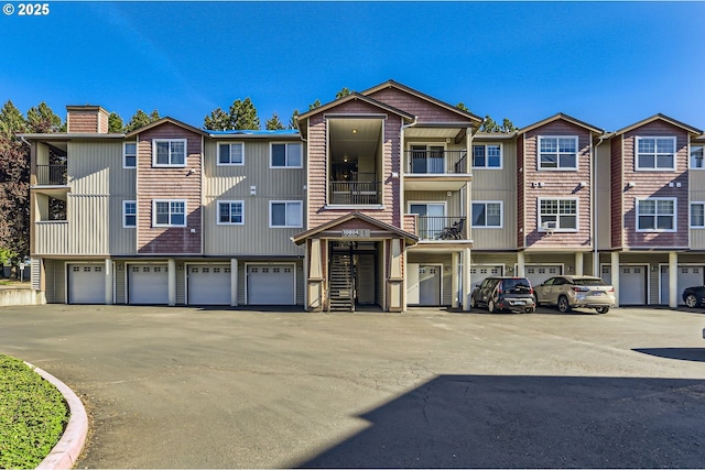 townhome / multi-family property featuring an attached garage, a chimney, and driveway