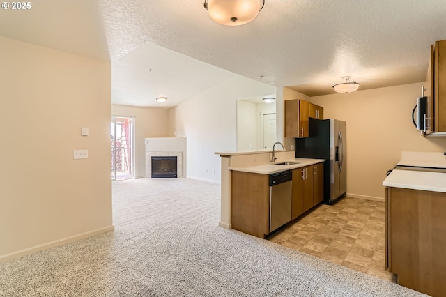 kitchen with appliances with stainless steel finishes, a sink, brown cabinetry, light countertops, and baseboards