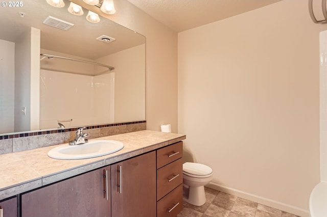 bathroom with toilet, a shower, vanity, and baseboards