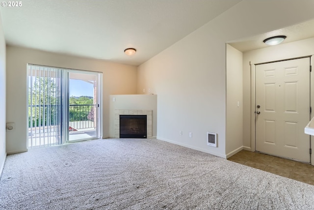 unfurnished living room featuring carpet flooring, a tile fireplace, and baseboards