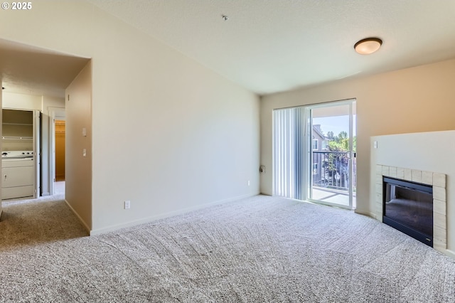 unfurnished living room featuring carpet flooring, washer / dryer, a fireplace, and baseboards