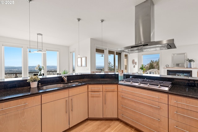 kitchen featuring pendant lighting, dark stone counters, sink, and exhaust hood