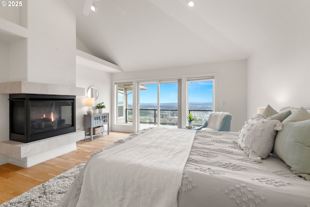 bedroom featuring ceiling fan, access to exterior, high vaulted ceiling, wood-type flooring, and a fireplace