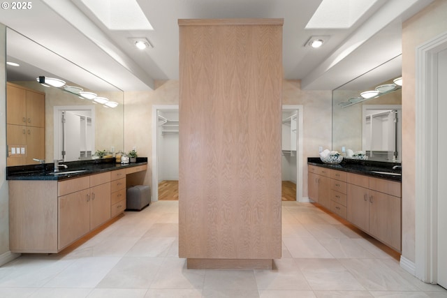 bathroom with vanity, a skylight, and tile patterned flooring