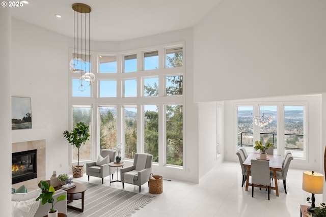 interior space featuring a tiled fireplace, a high ceiling, a wealth of natural light, and an inviting chandelier