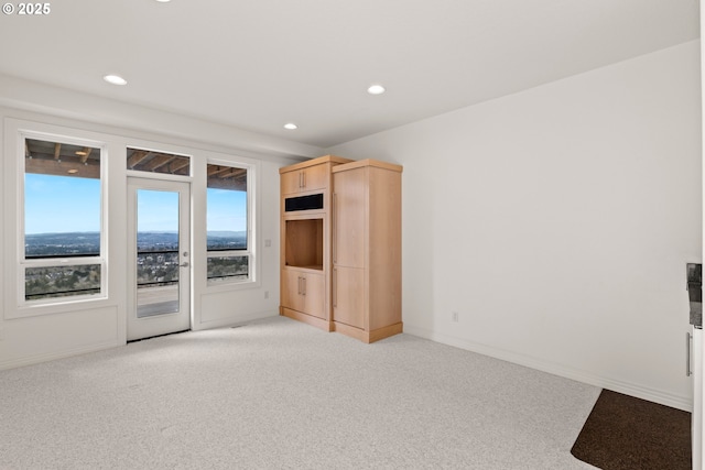 unfurnished bedroom featuring multiple windows, light colored carpet, and access to exterior