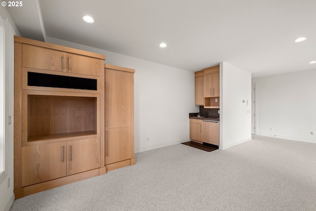 kitchen featuring dishwashing machine, light brown cabinets, and light colored carpet