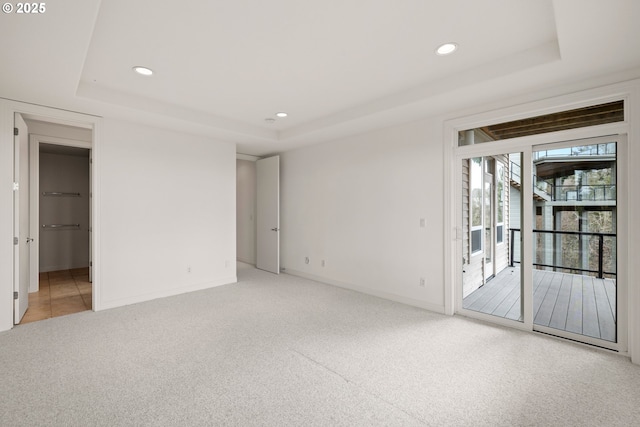 carpeted spare room featuring a tray ceiling