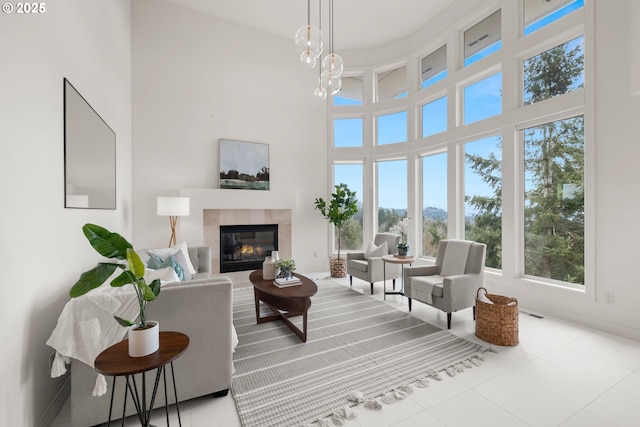 tiled living room featuring an inviting chandelier, a towering ceiling, and a fireplace