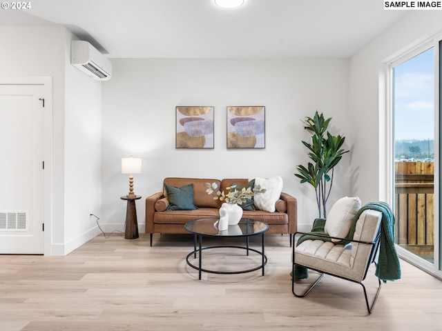 living area featuring an AC wall unit, baseboards, visible vents, and light wood-style flooring