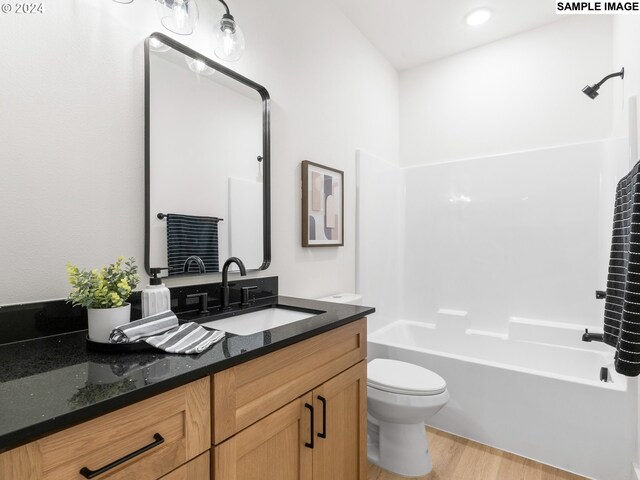 full bathroom featuring toilet, washtub / shower combination, wood finished floors, and vanity