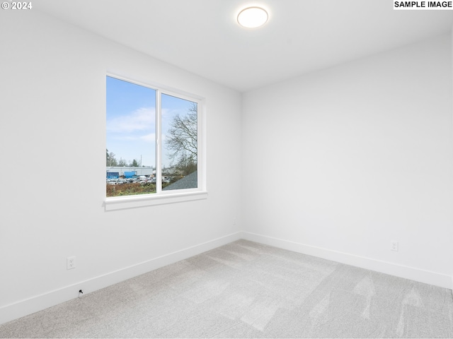 empty room featuring baseboards and light carpet