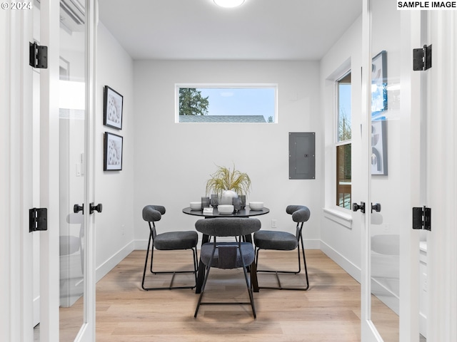 dining area with baseboards, light wood-style floors, french doors, and electric panel