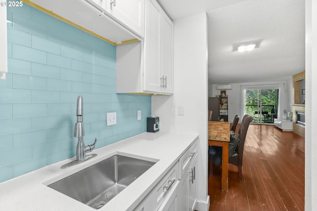12622 NW Barnes Rd Unit 6, Portland, OR 97229 - kitchen featuring a sink, white cabinetry, light countertops, decorative backsplash, and a textured ceiling