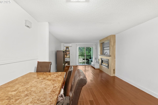 12622 NW Barnes Rd Unit 6, Portland, OR 97229 - dining room with wood finished floors, a fireplace, an AC wall unit, a textured ceiling, and baseboards