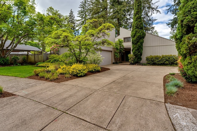 view of side of home with a yard, an attached garage, fence, and driveway