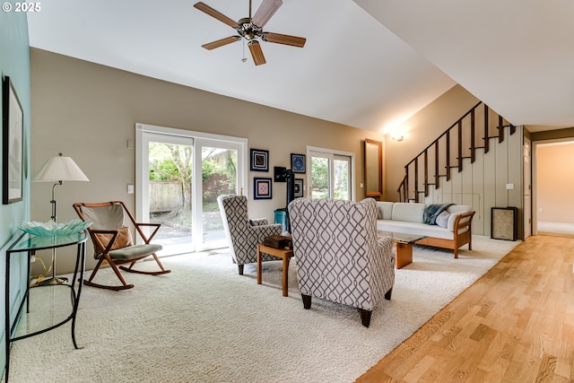 living room featuring ceiling fan, vaulted ceiling, stairs, and wood finished floors