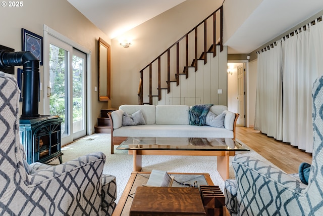 living area featuring light wood-style floors, a wood stove, a wealth of natural light, and stairway