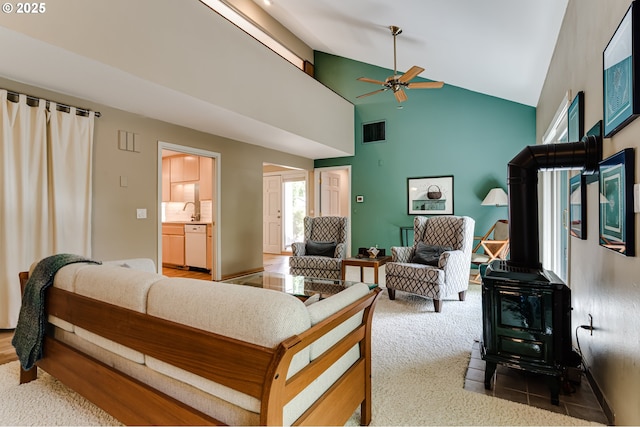 carpeted living room featuring a sink, a wood stove, high vaulted ceiling, a ceiling fan, and visible vents