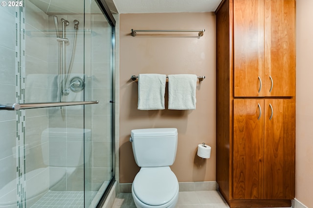 full bathroom with baseboards, tile patterned flooring, a shower stall, and toilet