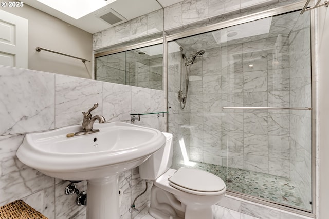 full bath featuring toilet, marble finish floor, tile walls, visible vents, and a stall shower
