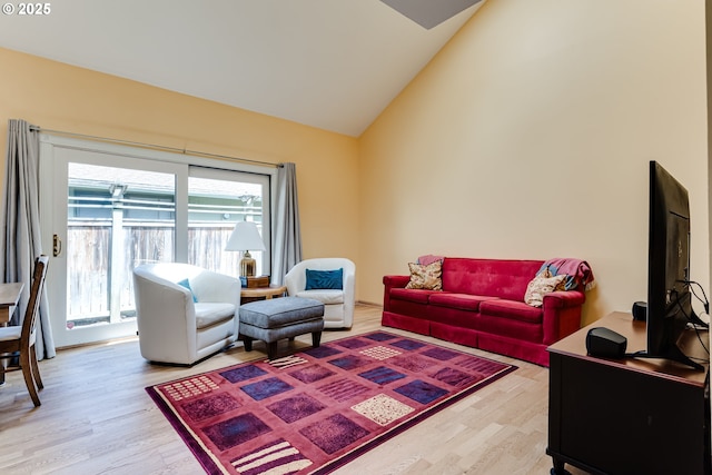 living room featuring light wood-style flooring and vaulted ceiling
