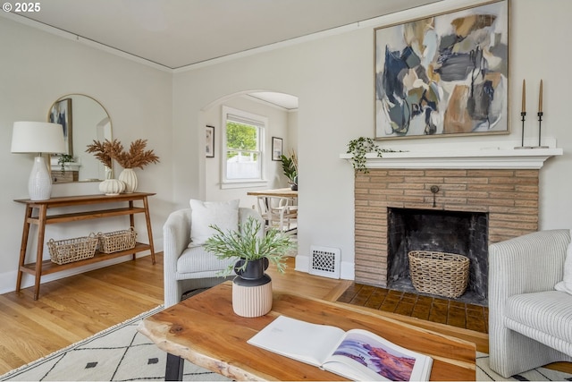 3737 NE 74th Ave, Portland, OR 97213 - living area with arched walkways, a brick fireplace, wood finished floors, and crown molding