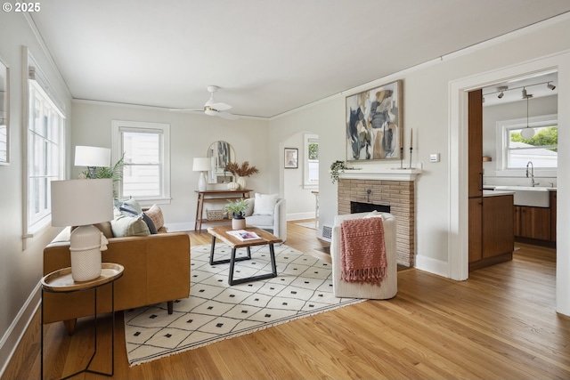 3737 NE 74th Ave, Portland, OR 97213 - living room featuring light wood-style floors, a brick fireplace, ceiling fan, baseboards, and arched walkways
