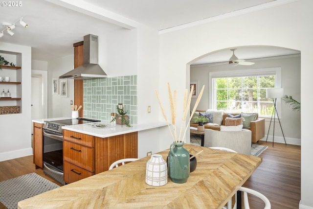 3737 NE 74th Ave, Portland, OR 97213 - kitchen featuring wall chimney exhaust hood, stainless steel range with electric stovetop, arched walkways, crown molding, and wood finished floors
