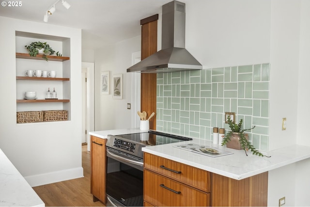3737 NE 74th Ave, Portland, OR 97213 - kitchen with wall chimney range hood, stainless steel range with electric cooktop, brown cabinets, decorative backsplash, and light wood-style floors