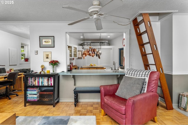 interior space with ceiling fan, kitchen peninsula, a textured ceiling, and light parquet floors