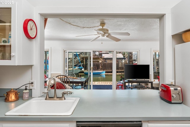 kitchen with ceiling fan, sink, dishwashing machine, and a textured ceiling