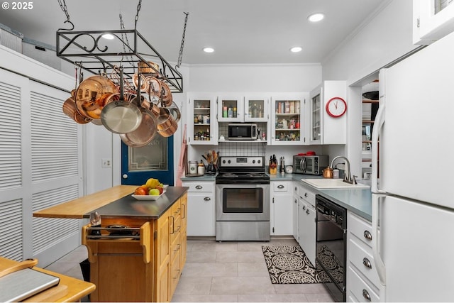 kitchen with stainless steel appliances, crown molding, sink, light tile patterned floors, and white cabinetry